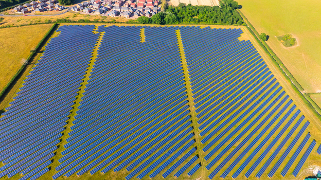Aerial view of large solar farm with rows of photovoltaic panels installed in a rural field near residential houses Dorset England United Kingdom. Aerial view of large solar farm with rows of photovoltaic panels installed in a rural field near residential houses Dorset England United Kingdom.