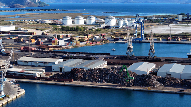 Aerial view of the Port of Ploce in Croatia featuring industrial storage tanks shipping containers cranes warehouses and piles of scrap metal along the waterfront. Aerial view of the Port of Ploce in Croatia featuring industrial storage tanks shipping containers cranes warehouses and piles of scrap metal along the waterfront.