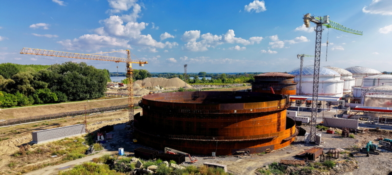 Aerial view of the construction site of a large refinery oil storage tank with cranes industrial equipment and surrounding landscape in Kovin Vojvodina Serbia. Aerial view of the construction site of a large refinery oil storage tank with cranes industrial equipment and surrounding landscape in Kovin Vojvodina Serbia.