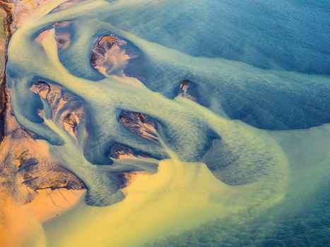 Aerial view of a glacial river delta with intricate sediment patterns and blue water channels flowing into the sea in Iceland. Aerial view of a glacial river delta with intricate sediment patterns and blue water channels flowing into the sea in Iceland.
