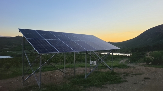 View of a solar panel array installed in a rural landscape with rolling hills a small pond and sunset lighting in Hoeko Western Cape South Africa. View of a solar panel array installed in a rural landscape with rolling hills a small pond and sunset lighting in Hoeko Western Cape South Africa.