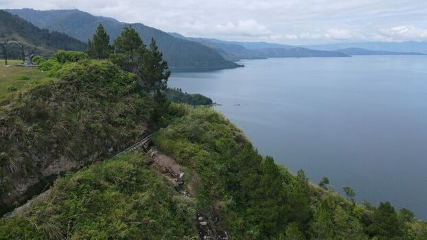 Aerial view of Tara Bunga overlooking the vast waters of Lake Toba with lush green hills and pine trees in Tampahan North Sumatra Indonesia. Aerial view of Tara Bunga overlooking the vast waters of Lake Toba with lush green hills and pine trees in Tampahan North Sumatra Indonesia.
