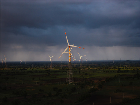 Aerial view of wind turbines standing in a rural landscape under a dramatic stormy sky in Hampi Karnataka India.