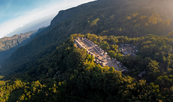 Aerial view of Bena Traditional Village featuring thatched roof houses and megalithic stones nestled in lush green mountains of Kecamatan Jerebuu Nusa Tenggara Timur Indonesia.