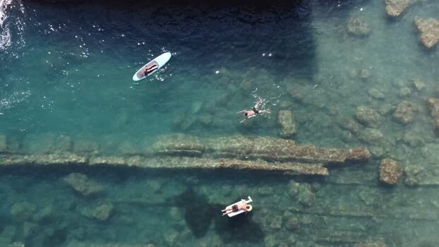 Aerial view of people swimming and paddleboarding in clear water Italy. Aerial view of people swimming and paddleboarding in clear water Italy.