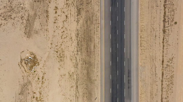 Aerial view of a straight highway cutting through the arid desert landscape in the United States.