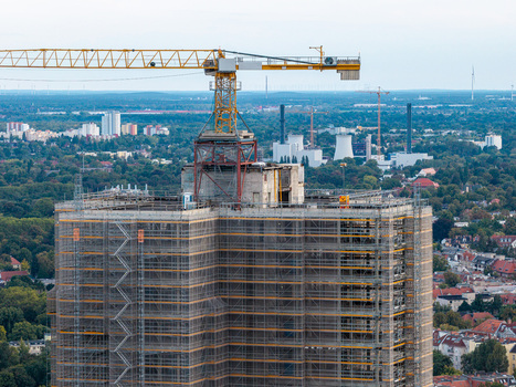 Aerial view of Steglitzer Kreisel under renovation with scaffolding and a yellow construction crane on top overlooking the urban landscape of Berlin Berlin Germany. Aerial view of Steglitzer Kreisel under renovation with scaffolding and a yellow construction crane on top overlooking the urban landscape of Berlin Berlin Germany.