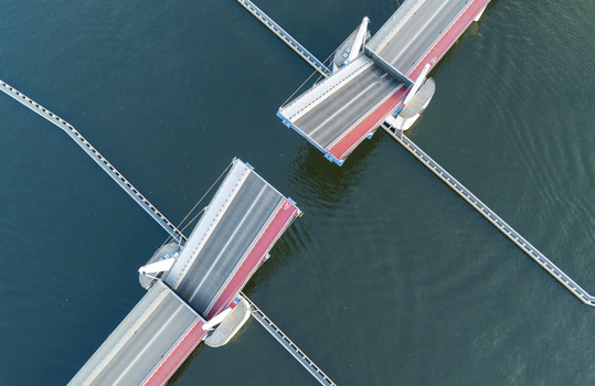 Aerial view of the Sobieszewo drawbridge in an open position over the Martwa Wisla river with calm water and clear lighting Gdansk Pomeranian Voivodeship Poland.