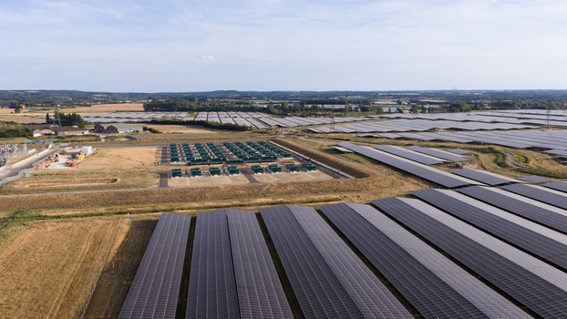 Aerial view of a large scale solar farm featuring rows of photovoltaic panels and a central battery energy storage system in the rural landscape of London England United Kingdom.