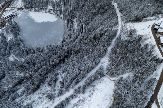 Aerial view of Mummelsee frozen lake surrounded by snow covered pine forests and winter landscape in Seebach Baden Wurttemberg Germany. Aerial view of Mummelsee frozen lake surrounded by snow covered pine forests and winter landscape in Seebach Baden Wurttemberg Germany.