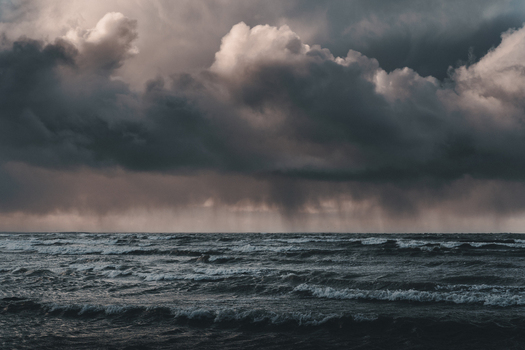 View of the stormy Baltic Sea off the coast of Vormsi with dark heavy rain clouds and rough churning waves under a dramatic moody sky in Laane County Estonia.