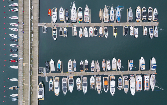 Aerial view of Sopot marina featuring numerous yachts and motorboats docked in orderly rows along wooden piers in the Baltic Sea Sopot Pomeranian Voivodeship Poland. Aerial view of Sopot marina featuring numerous yachts and motorboats docked in orderly rows along wooden piers in the Baltic Sea Sopot Pomeranian Voivodeship Poland.