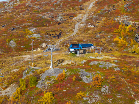 Aerial view of a ski lift station nestled in a mountainous landscape with vibrant autumn foliage rocky terrain and a winding dirt path in Bjorli Innlandet Norway. Aerial view of a ski lift station nestled in a mountainous landscape with vibrant autumn foliage rocky terrain and a winding dirt path in Bjorli Innlandet Norway.