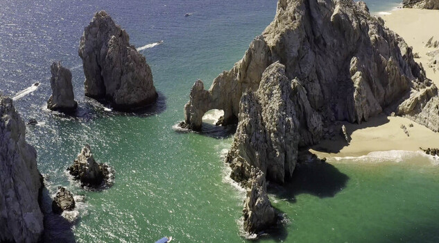 Aerial view of El Arco rock formation surrounded by turquoise waters sandy beaches and rocky cliffs in Cabo San Lucas Baja California Sur Mexico.