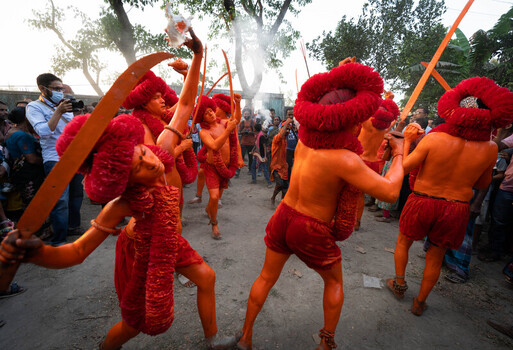 Munshiganj Bangladesh 13 April 2025 View of vividly painted performers in striking red costumes and fluffy headdresses wielding ceremonial swords amidst a festive crowd. Munshiganj Bangladesh 13 April 2025 View of vividly painted performers in striking red costumes and fluffy headdresses wielding ceremonial swords amidst a festive crowd.