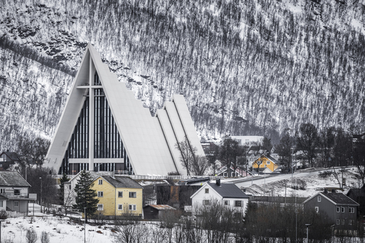 Tromso Norway 11 March 2026 View of the Arctic Cathedral with its iconic triangular architecture against a snowy mountain backdrop and residential houses. Tromso Norway 11 March 2026 View of the Arctic Cathedral with its iconic triangular architecture against a snowy mountain backdrop and residential houses.
