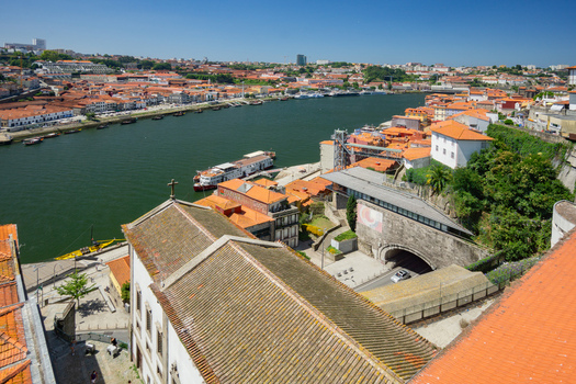 Aerial view of terracotta roofs cascade towards the Douro River reflecting the azure sky above the Ribeira district Porto Porto District Portugal. Aerial view of terracotta roofs cascade towards the Douro River reflecting the azure sky above the Ribeira district Porto Porto District Portugal.