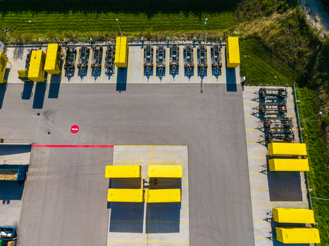 Aerial view of Logistikzentrum Allhaming featuring rows of yellow shipping containers and truck chassis parked in an organized logistics yard in Allhaming Oberosterreich Austria. Aerial view of Logistikzentrum Allhaming featuring rows of yellow shipping containers and truck chassis parked in an organized logistics yard in Allhaming Oberosterreich Austria.