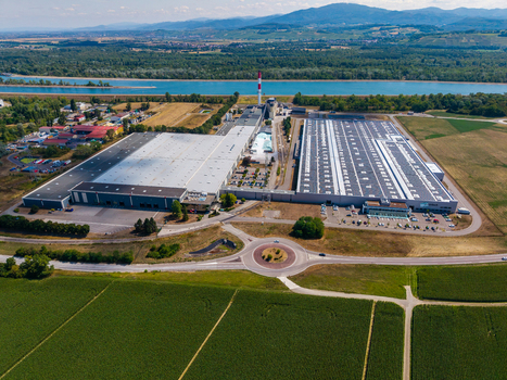 Aerial view of the Glas Troesch Alsace SAS industrial facility featuring large factory buildings with solar panels and a tall chimney in Hombourg Grand Est France.