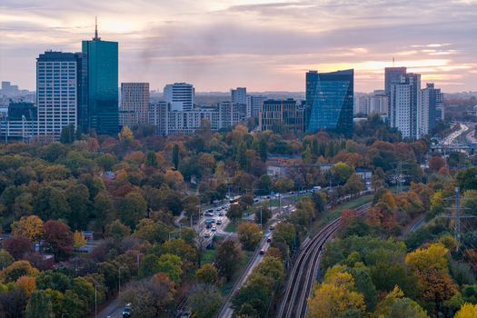 Aerial view of the modern skyline of Warsaw featuring skyscrapers rising above autumn trees with railway tracks and traffic in the foreground in Warsaw Masovian Voivodeship Poland. Aerial view of the modern skyline of Warsaw featuring skyscrapers rising above autumn trees with railway tracks and traffic in the foreground in Warsaw Masovian Voivodeship Poland.