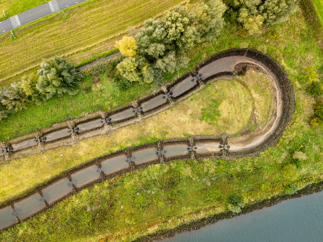 Aerial view of Sluis en stuwcomplex Hagestein showing a fish ladder stone lined banks and surrounding green fields in Hagestein Utrecht Netherlands.