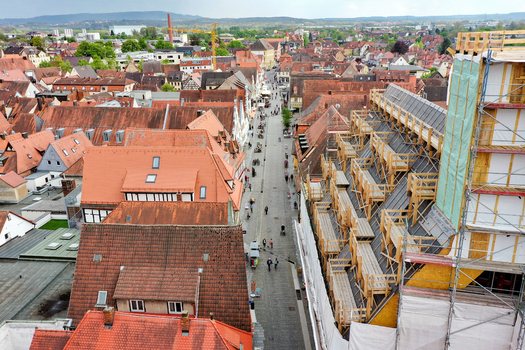 Aerial view of Rathaus Forchheim under renovation with scaffolding historic red tiled rooftops and people walking along the cobblestone street in Forchheim Bayern Germany.