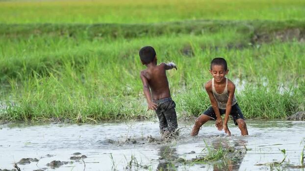 View of children playing in a muddy field in Bogura Bangladesh.