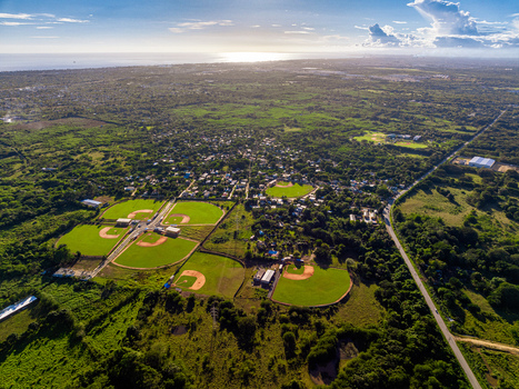 Aerial view of Quality Baseball Academy with baseball fields featuring green grass and dirt infields in San Antonio de Guerra Santo Domingo Province Dominican Republic. Aerial view of Quality Baseball Academy with baseball fields featuring green grass and dirt infields in San Antonio de Guerra Santo Domingo Province Dominican Republic.