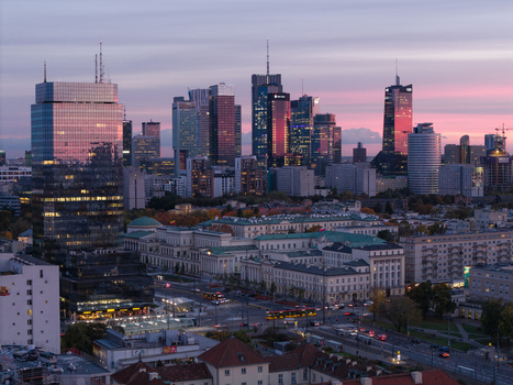 Aerial view of modern skyscrapers with glass facades reflecting a pink sunset sky over the urban landscape and city streets in Poland. Aerial view of modern skyscrapers with glass facades reflecting a pink sunset sky over the urban landscape and city streets in Poland.
