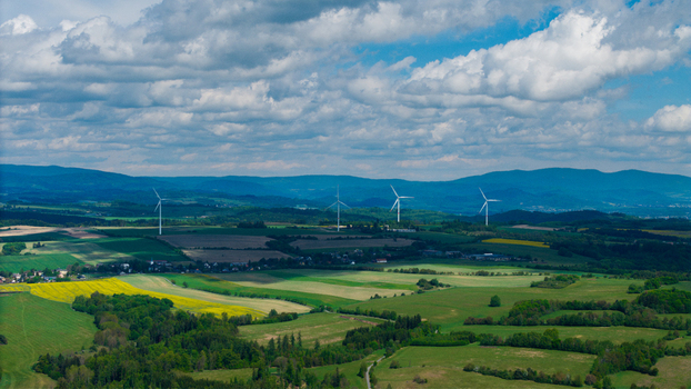 Aerial view of Zipotin wind farm with white turbines standing among green fields and forests under a cloudy sky in Gruna Pardubicky kraj Czechia. Aerial view of Zipotin wind farm with white turbines standing among green fields and forests under a cloudy sky in Gruna Pardubicky kraj Czechia.