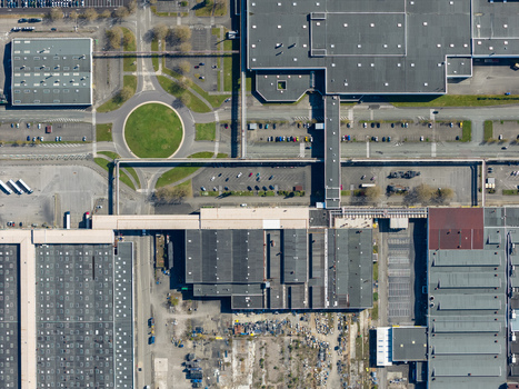 Aerial view of industrial landscape showcasing the stark geometry of buildings roads and parking lots contrasting with the verdant roundabout Sausheim Grand Est France.