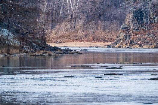 View of flowing water reflecting the sky and bare trees along the rocky banks in the serene Scott s Run Nature Preserve Scott s Run Virginia United States. View of flowing water reflecting the sky and bare trees along the rocky banks in the serene Scott s Run Nature Preserve Scott s Run Virginia United States.