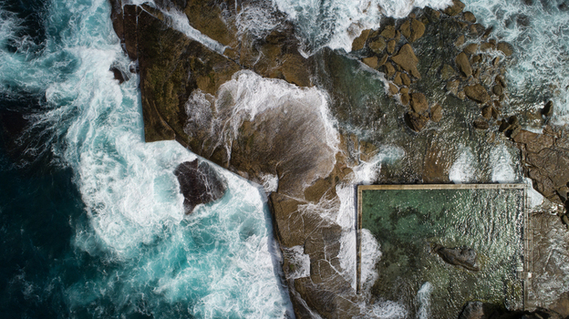 Aerial view of Newport Rock Pool with waves crashing against rugged rocks and turquoise water filling the ocean pool in Sydney New South Wales Australia.