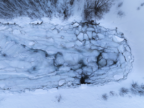 Aerial view of a frozen river with ice floes and snow covered banks in the winter landscape of Tromso Troms Norway. Aerial view of a frozen river with ice floes and snow covered banks in the winter landscape of Tromso Troms Norway.