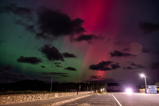 View of the vibrant green and red Aurora Borealis illuminating the night sky above a coastal road in Portnoo County Donegal Ireland. View of the vibrant green and red Aurora Borealis illuminating the night sky above a coastal road in Portnoo County Donegal Ireland.