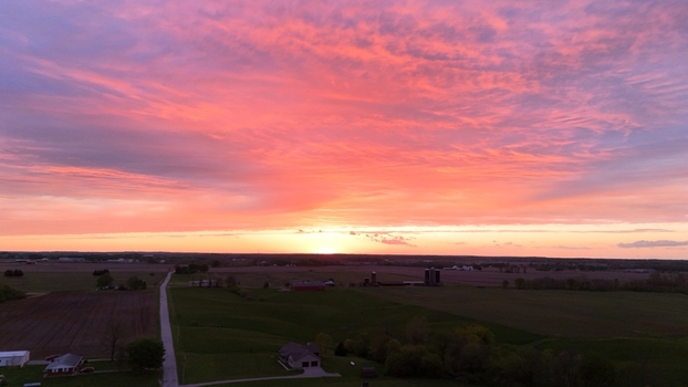 Aerial view of a vibrant pink and orange sunset over rural farmlands with green fields and farmhouses in Indianapolis USA. Aerial view of a vibrant pink and orange sunset over rural farmlands with green fields and farmhouses in Indianapolis USA.