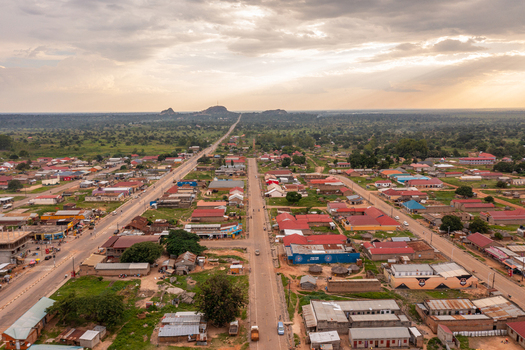 Aerial view of Katakwi Town Council featuring a grid of buildings with red roofs a main road and distant hills under a cloudy sunset sky in Katakwi Eastern Region Uganda. Aerial view of Katakwi Town Council featuring a grid of buildings with red roofs a main road and distant hills under a cloudy sunset sky in Katakwi Eastern Region Uganda.