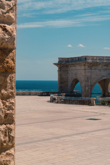 View of the Bastione di Saint Remy stone terrace and neoclassical arches overlooking the blue Mediterranean Sea under a clear sky in Cagliari Sardegna Italy. View of the Bastione di Saint Remy stone terrace and neoclassical arches overlooking the blue Mediterranean Sea under a clear sky in Cagliari Sardegna Italy.