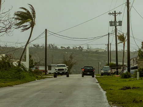 San Jose Tinian Northern Mariana Islands 06 July 2026 View of a street during a typhoon with strong winds bending palm trees dark skies and vehicles driving on a wet road. San Jose Tinian Northern Mariana Islands 06 July 2026 View of a street during a typhoon with strong winds bending palm trees dark skies and vehicles driving on a wet road.