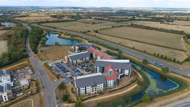 Aerial view of Wixams Retirement Village with modern residential buildings red roofs parking lots and surrounding ponds located in Bedford England United Kingdom.