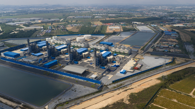 Aerial view of the Gulf Pluak Daeng Power Plant featuring blue industrial buildings and large water reservoirs in Map Yang Phon Rayong Thailand.