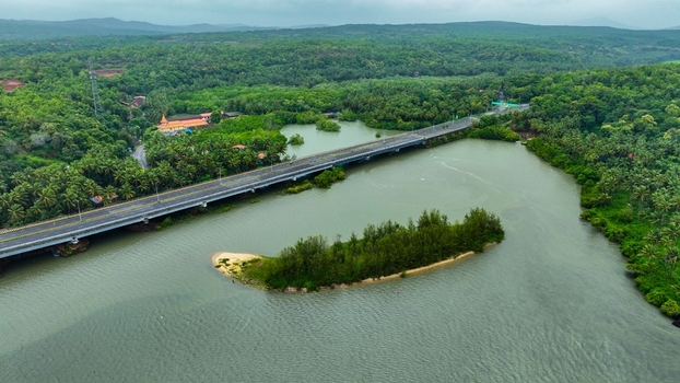 Aerial view of the Galgibaga Bridge spanning the river surrounded by dense tropical vegetation and palm trees in Canacona Goa India.