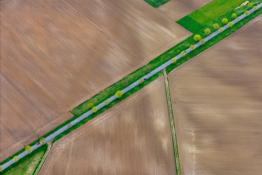Aerial view of a straight road cutting through fields of brown and green the landscape a patchwork of earth tones Neuf Brisach Grand Est France.
