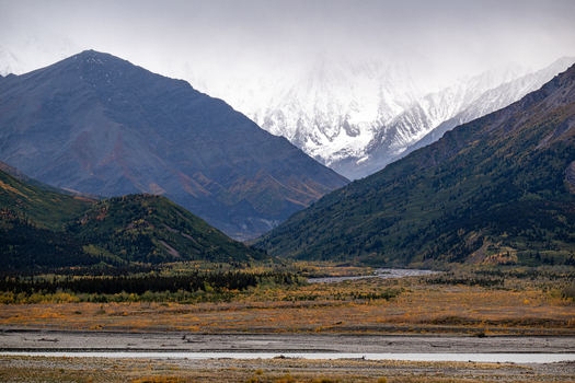 View of the rugged mountain landscape near Paxson with snow capped peaks a winding river and autumn foliage under an overcast sky in Paxson Alaska United States. View of the rugged mountain landscape near Paxson with snow capped peaks a winding river and autumn foliage under an overcast sky in Paxson Alaska United States.