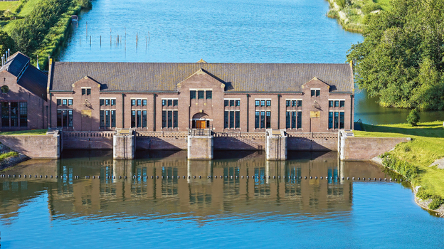 Aerial view of the Wouda pumping station a historic brick building with large windows situated along a canal with calm water reflecting the structure in Lemmer Friesland Netherlands.