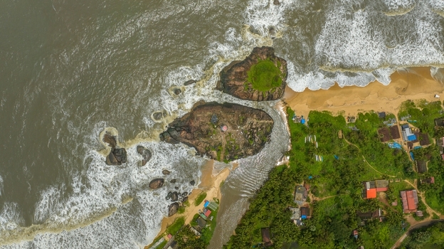 Aerial view of Kapu Light House on rocky outcrops surrounded by the Arabian Sea with sandy beaches and lush coastal vegetation in Udupi Karnataka India.