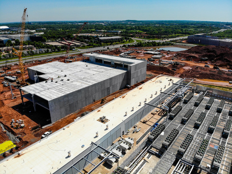 Aerial view of a large data center construction site featuring concrete buildings industrial cooling units construction cranes and earthworks in Ashburn Virginia United States. Aerial view of a large data center construction site featuring concrete buildings industrial cooling units construction cranes and earthworks in Ashburn Virginia United States.