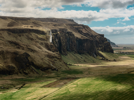 Aerial view of Seljalandsfoss waterfall cascading down a rugged cliffside with green fields and dramatic clouds in Rangarthing eystra Iceland. Aerial view of Seljalandsfoss waterfall cascading down a rugged cliffside with green fields and dramatic clouds in Rangarthing eystra Iceland.