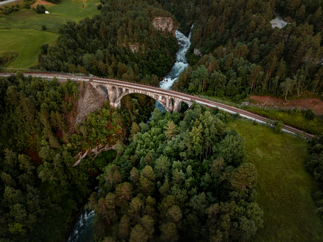 View of Kylling Bridge spanning the Rauma River surrounded by dense pine forests and rocky terrain in Rauma Municipality More og Romsdal Norway. View of Kylling Bridge spanning the Rauma River surrounded by dense pine forests and rocky terrain in Rauma Municipality More og Romsdal Norway.