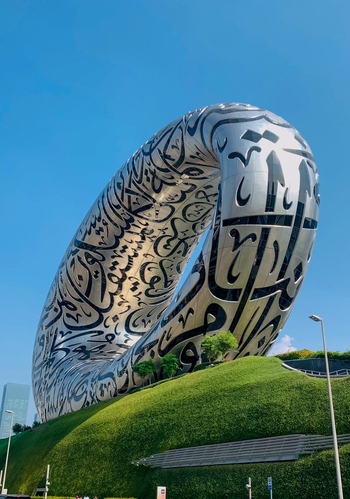 View of The Museum of the Future with its iconic torus shaped structure covered in Arabic calligraphy set against a clear blue sky in Dubai Dubai United Arab Emirates. View of The Museum of the Future with its iconic torus shaped structure covered in Arabic calligraphy set against a clear blue sky in Dubai Dubai United Arab Emirates.